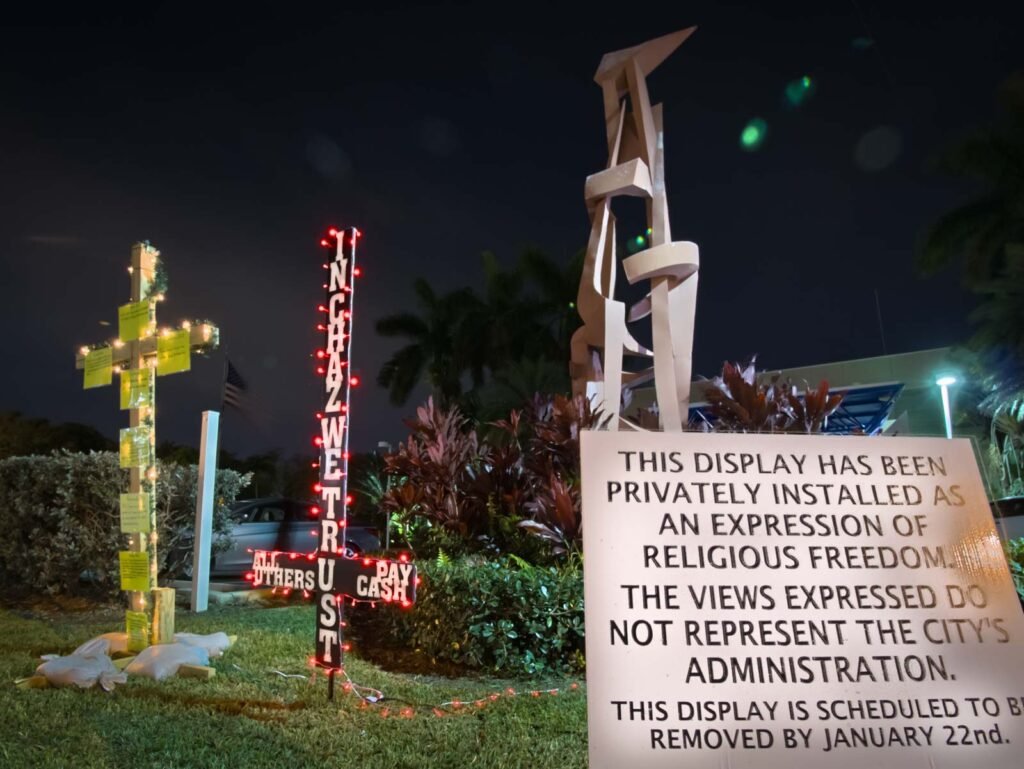 Upside-down cross reading "In Chaz We Trust, All Others Pay Cash", installed at Hallandale Beach City Hall in January 20