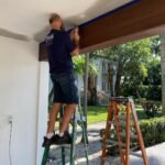Architectural Foam Florida installer in a company shirt setting a foam beam at a home entrance